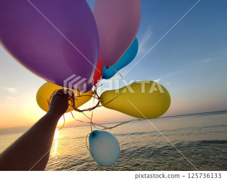 Woman playing with many colorful balloons on the sandy beach of the seashore near the sea at sunrise and sunset. Relax and have fun. Slow motion Woman playing with many colorful balloons on the sandy beach of the seashore near the sea at sunrise and sunset. Relax and have fun. Slow motion 125736133