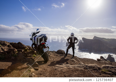 Enduro Motorcycle with Driver Posing on Sea Cliff , Madeira island 125736407