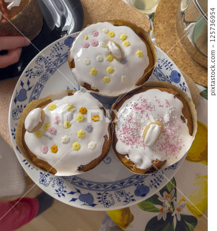 Easter cakes with sprinkles on white glaze. Easter cakes on a plate. Homemade baking, preparation for the spring holiday. Easter cakes with sprinkles on white glaze. Easter cakes on a plate. Homemade baking, preparation for the spring holiday. 125736954