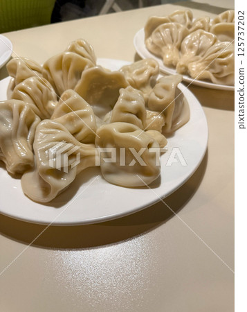 Plates of freshly cooked Georgian khinkali dumplings served in a traditional restaurant in Tbilisi, Georgia, highlighting local cuisine and cultural dining experience 125737202