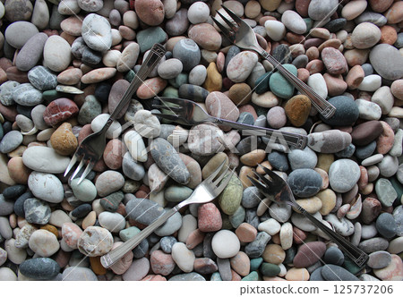 Same Three Pronged Forks Scattered On Smooth Sea Pebbles Top View Stock Photo 125737206