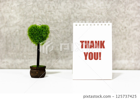 Words of gratitude on a notebook , next to a heart-shaped flower. Thank you Words of gratitude on a notebook , next to a heart-shaped flower. Thank you 125737425