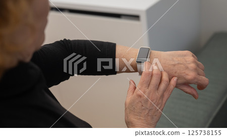 Elderly Caucasian woman looking at smart watch. Close-up of hands. Elderly Caucasian woman looking at smart watch. Close-up of hands. 125738155