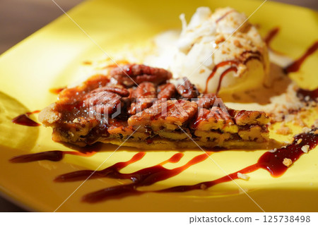 Homemade pecan pie with caramel sauce and vanilla ice cream Homemade pecan pie with caramel sauce and vanilla ice cream 125738498