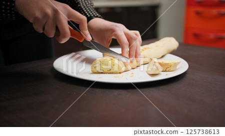 In a Home Kitchen A Hand Cuts Cantucci Biscuits Before Second Baking In Oven In a Home Kitchen A Hand Cuts Cantucci Biscuits Before Second Baking In Oven 125738613