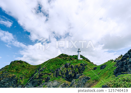 A dynamic view looking up at the Okanzaki Lighthouse, Ishigaki Island. Okanzaki Lighthouse stands tall in the natural surroundings of Ishigaki Island. 125740419