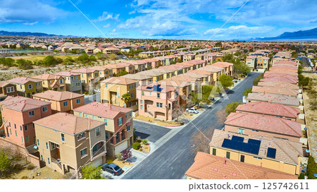 Aerial of Suburban Desert Community with Solar Panels and Mountains 125742611