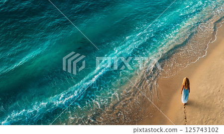 A woman walking along the shoreline and the emerald blue sea 125743102