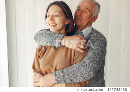 Grandfather at home. Old man with granddaughter. Senior in a gray sweater. 125743486