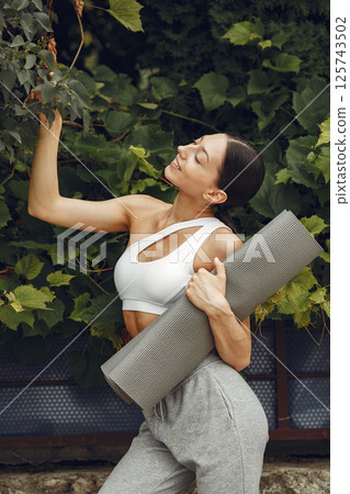 Pretty lady in a park. Brunette prepare to yoga. Girl in a sportsuit. 125743502