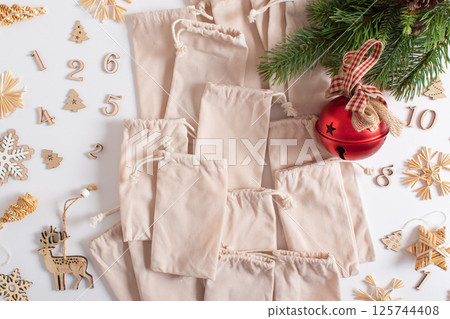 Christmas advent calendar with gift velvet bags and wooden numbers on a white background. Eco-friendly 125744408