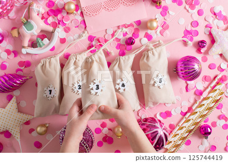 Christmas advent calendar with gift velvet bags on a pink background. Environmentally friendly. Christmas advent calendar with gift velvet bags on a pink background. Environmentally friendly. 125744419