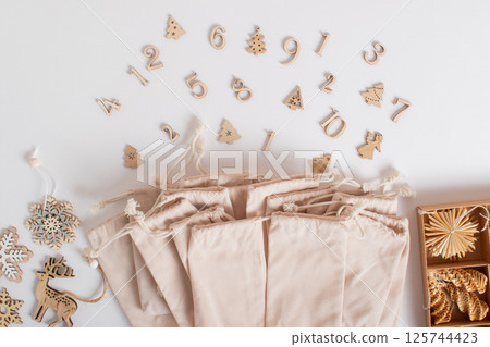 Christmas advent calendar with gift velvet bags and wooden numbers on a white background. Eco-friendly 125744423