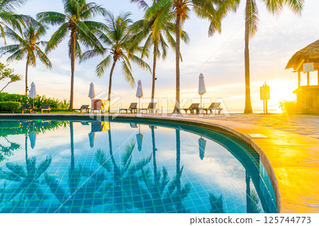 Umbrella and chair around swimming pool in hotel resort with sunrise in morning 125744773