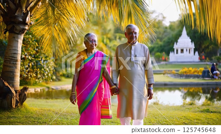 Elderly indian couple holding hands walking in a tropical park Elderly indian couple holding hands walking in a tropical park 125745648