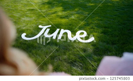 Woman looking at june writing on grass 125745803