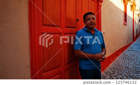 Man Leaning Against a Red Door in an Alley Man Leaning Against a Red Door in an Alley 125746132