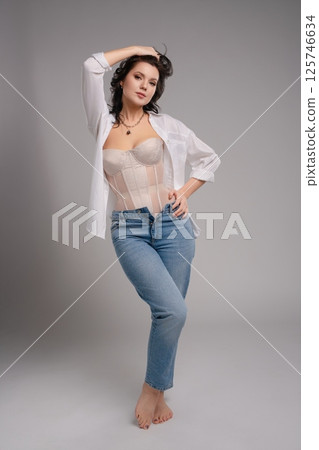 Elegant beauty poses in a corset and casual jeans for a fashion shoot 125746634