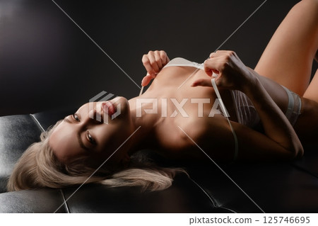 Woman poses in elegant lingerie on a dark background in a stylish setting Woman poses in elegant lingerie on a dark background in a stylish setting 125746695