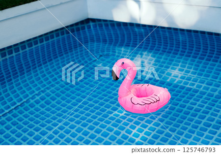 Inflatable pink flamingo floating in a clear blue swimming pool. Inflatable pink flamingo floating in a clear blue swimming pool. 125746793