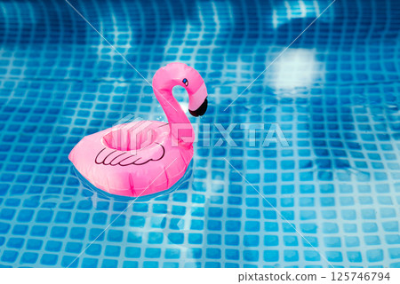 Inflatable pink flamingo floating in a clear blue swimming pool. Inflatable pink flamingo floating in a clear blue swimming pool. 125746794