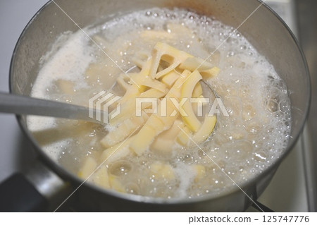 用米水將生竹筍（takenoko、竹筍、竹筍）放入鍋中煮至半熟。 125747776