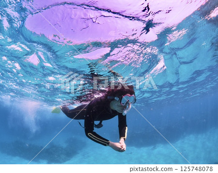 一位女士在石垣島的藍色海水中享受浮潛 125748078