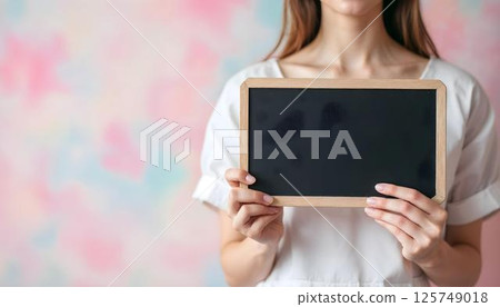 A woman confidently holds a blackboard, commemorating empowerment on International Women's Day 125749018