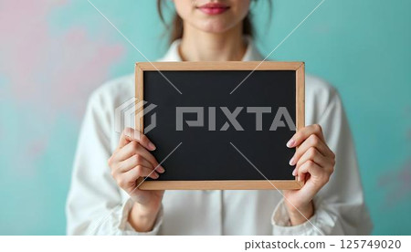 A woman lifts a blackboard, embodying the spirit of empowerment for International Women's Day 125749020