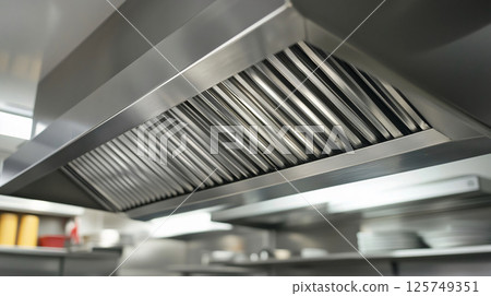 Large metallic extractor fan filtering the air in a restaurant kitchen 125749351