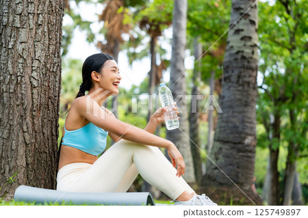 Young Asian woman in activewear sitting under a tree 125749897