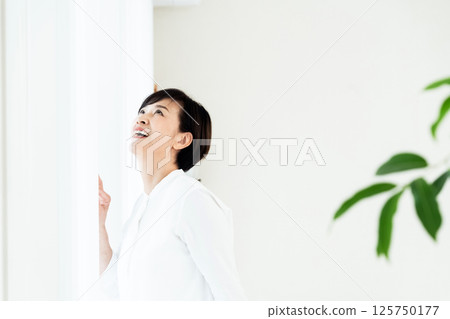 Senior woman standing at the window 125750177