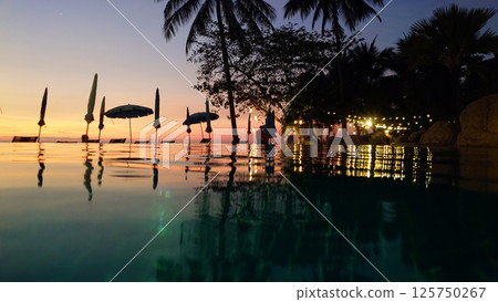 Infinity pool reflecting sunset and palm trees at dusk Infinity pool reflecting sunset and palm trees at dusk 125750267