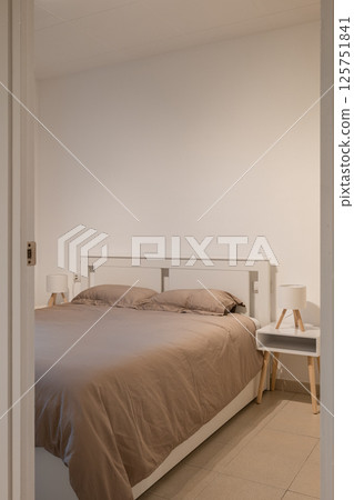 Minimalist bedroom with white bed frame, neutral bedding and two small nightstands Minimalist bedroom with white bed frame, neutral bedding and two small nightstands 125751841