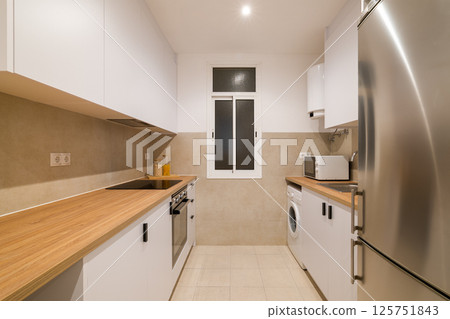 Bright kitchen with wood countertops, white cabinets and modern appliances in compact space 125751843