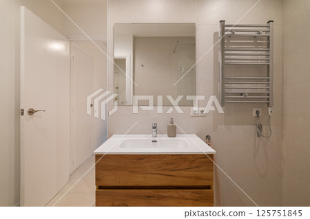Modern bathroom with wood vanity, large wall mirror, chrome towel warmer and glass shower area Modern bathroom with wood vanity, large wall mirror, chrome towel warmer and glass shower area 125751845
