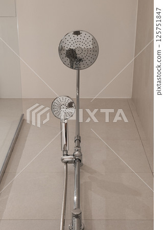 Low angle view of chrome shower fixture with large rain shower head and handheld shower attachment 125751847