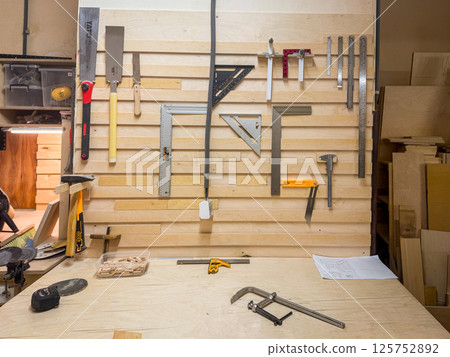Close-up of workshop tool wall featuring screwdriver, ruler, clamp, wrench, pliers, and precision carpentry gear for skilled work Close-up of workshop tool wall featuring screwdriver, ruler, clamp, wrench, pliers, and precision carpentry gear for skilled work 125752892