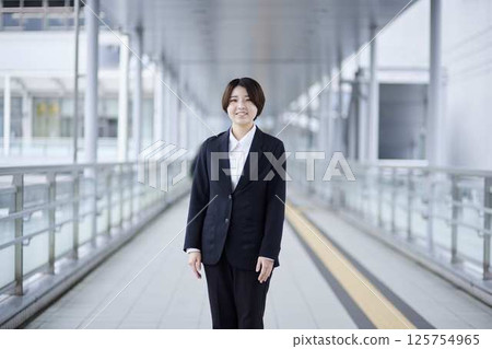 一位微笑的女商人站在人行天橋上。 一位微笑的女商人站在人行天橋上。 125754965