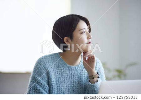 一位女大學生面帶微笑,低頭思考著,手中的筆抵著下巴。 一位女大學生面帶微笑,低頭思考著,手中的筆抵著下巴。 125755015