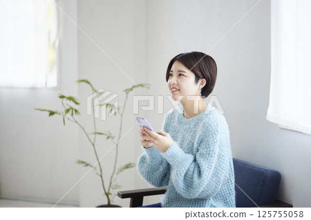 Young woman using a smartphone in her room Young woman using a smartphone in her room 125755058