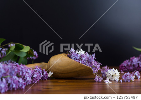 Purple lilac flowers in a wooden scoop on a black background 125755487
