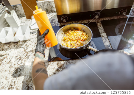 Deliciously Cooking Gourmet Pasta with Savory Sauce in a Modern Kitchen Setting and Atmosphere 125755855