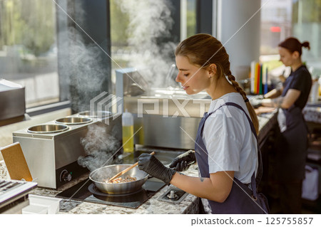 A talented chef is preparing a gourmet dish in a beautifully designed modern kitchen setting A talented chef is preparing a gourmet dish in a beautifully designed modern kitchen setting 125755857