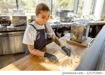 A Female Baker Diligently Preparing Mouthwatering Delicious Treats in a Bright Bakery Space 125755861