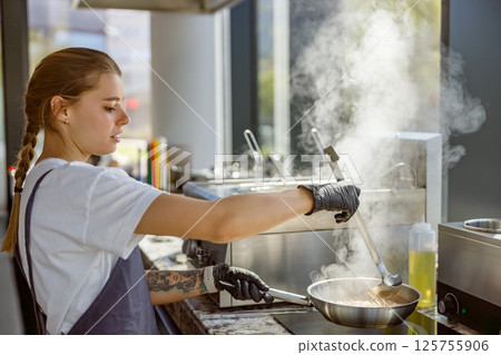 A Culinary Expert is skillfully Cooking in a Modern Kitchen while utilizing Steam technology 125755906