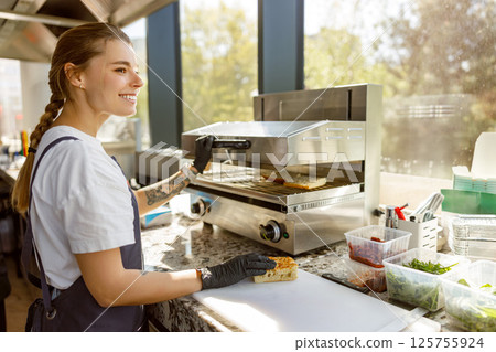 A Skilled Female Chef Expertly Preparing a Delicious Sandwich in a Modern Kitchen Environment A Skilled Female Chef Expertly Preparing a Delicious Sandwich in a Modern Kitchen Environment 125755924