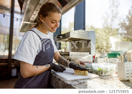A Smiling Chef Enthusiastically Preparing Fresh Ingredients in a Modern, Stylish Kitchen A Smiling Chef Enthusiastically Preparing Fresh Ingredients in a Modern, Stylish Kitchen 125755955