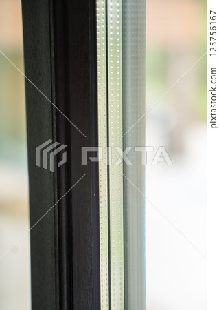 Textured aluminum frame with visible glazing spacer and forest background Textured aluminum frame with visible glazing spacer and forest background 125756167