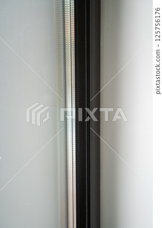 Macro photo of double-glazed window with perforated spacer and dark profile 125756176
